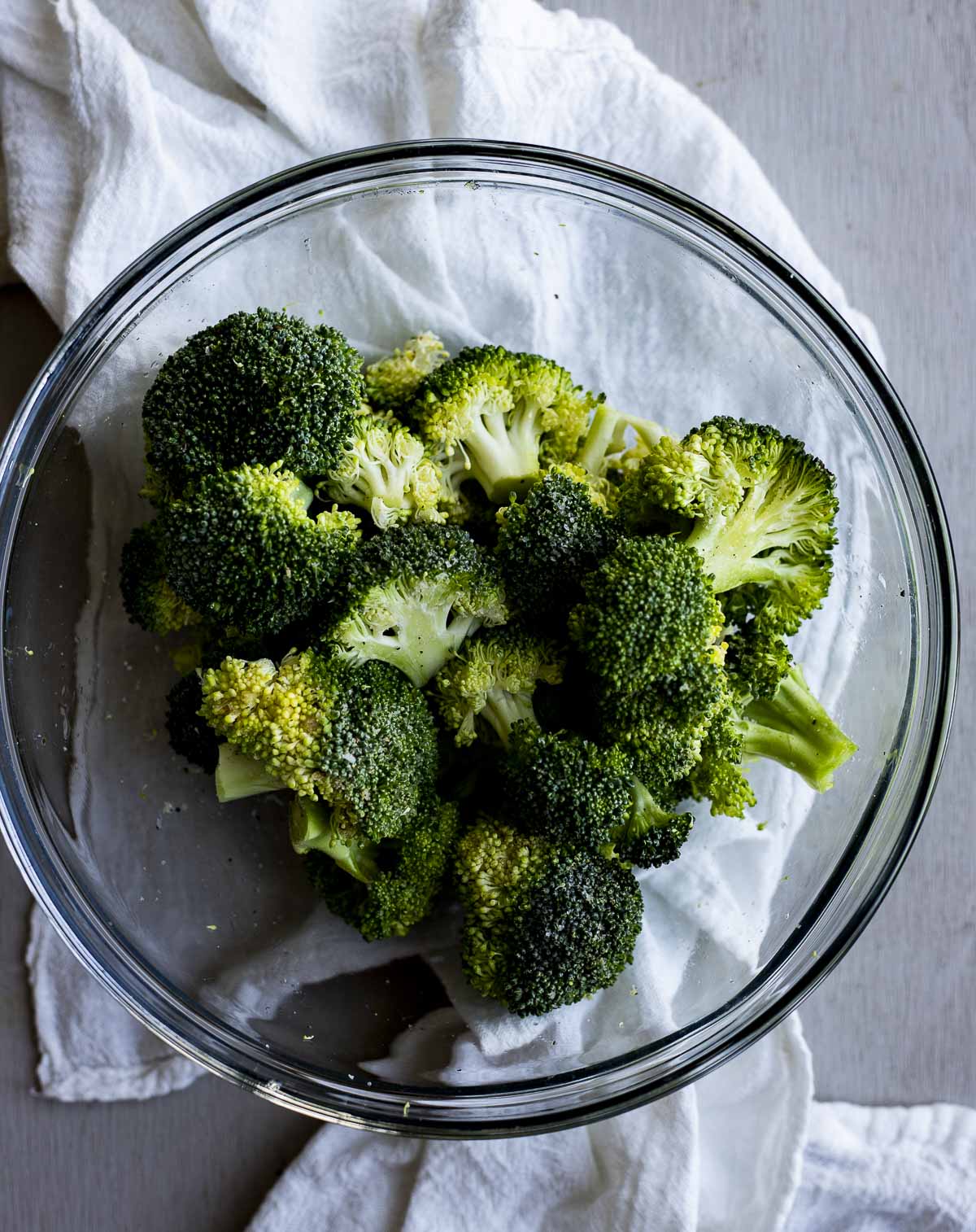 Raw broccoli florets in a glass bowl.