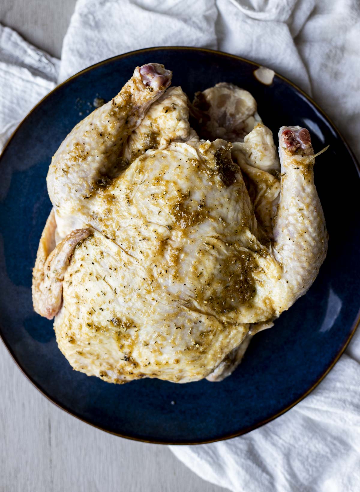 Overhead view of a seasoned whole chicken on a plate.