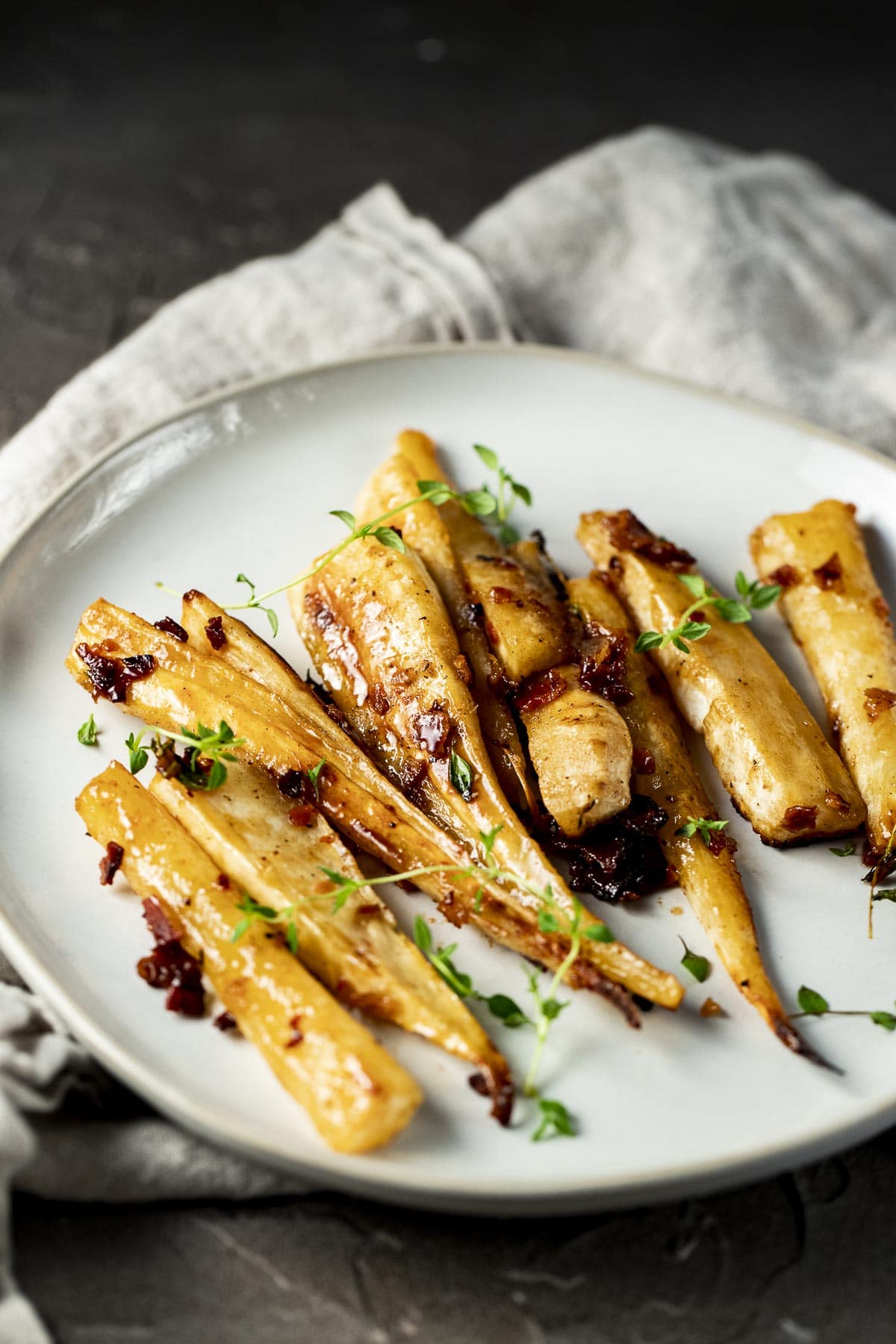 Side view of roasted parsnips on a plate.