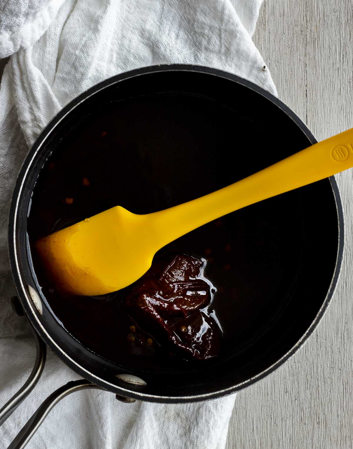 Glaze being stirred together in a saucepan with a spatula.