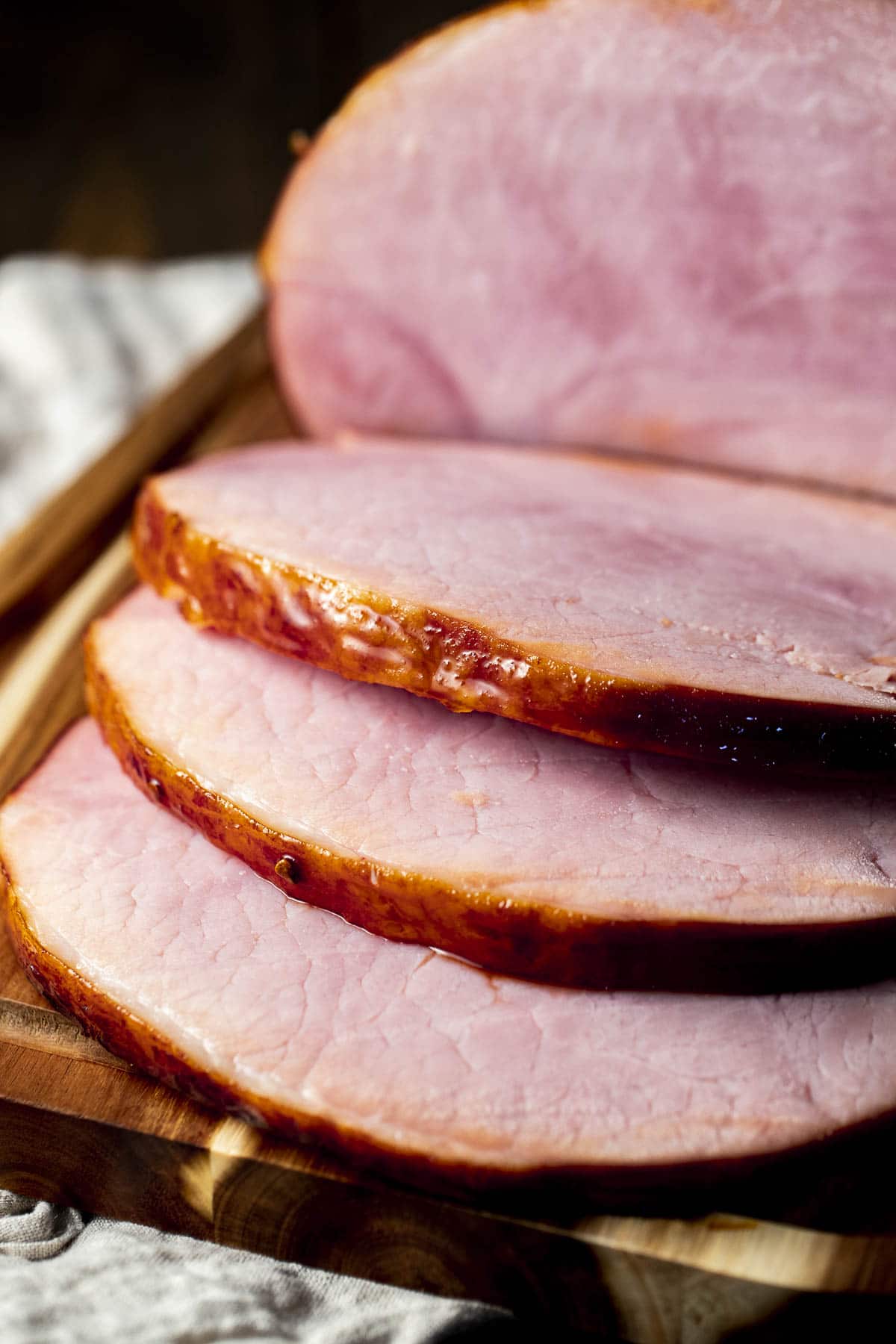 Side view of thick slices of ham on a wooden board.