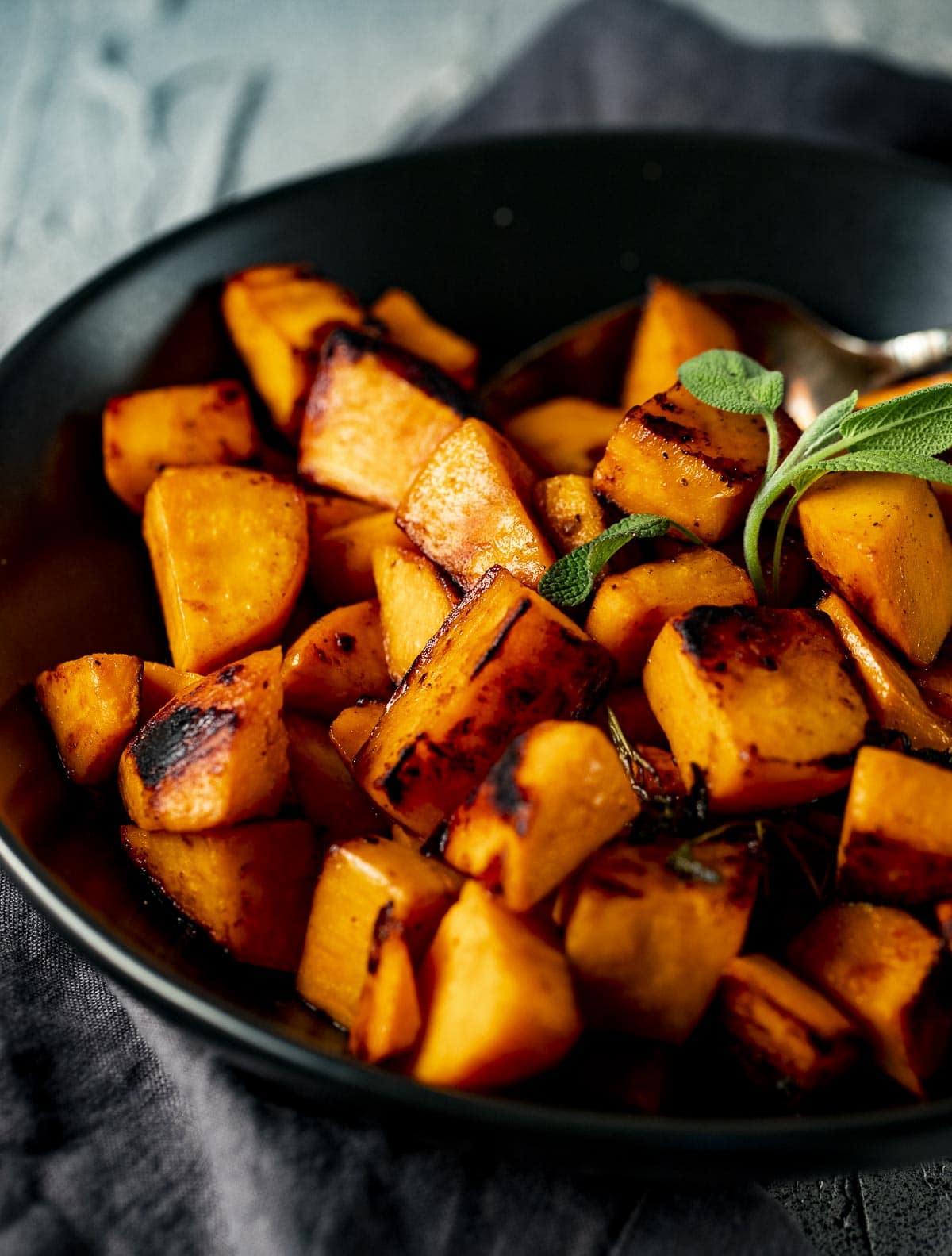 Side view of cooked sweet potatoes served in a black bowl.