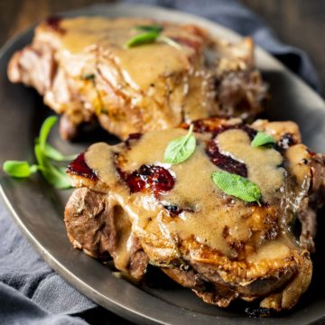 Two turkey thighs topped with gravy on a serving plate.
