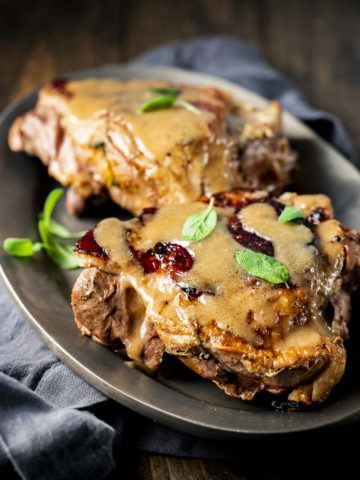 Two turkey thighs topped with gravy on a serving plate.