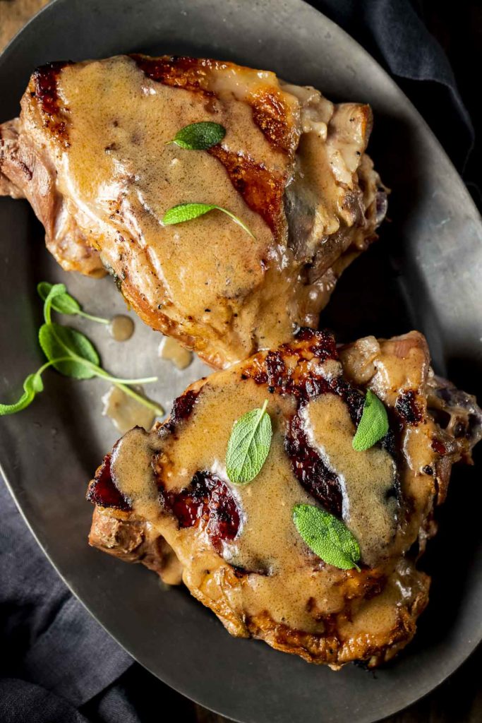 Overhead view of turkey thighs and gravy on a plate.