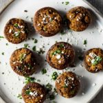 Overhead view of stuffed mushrooms on a plate with cilantro and cotija cheese on top.