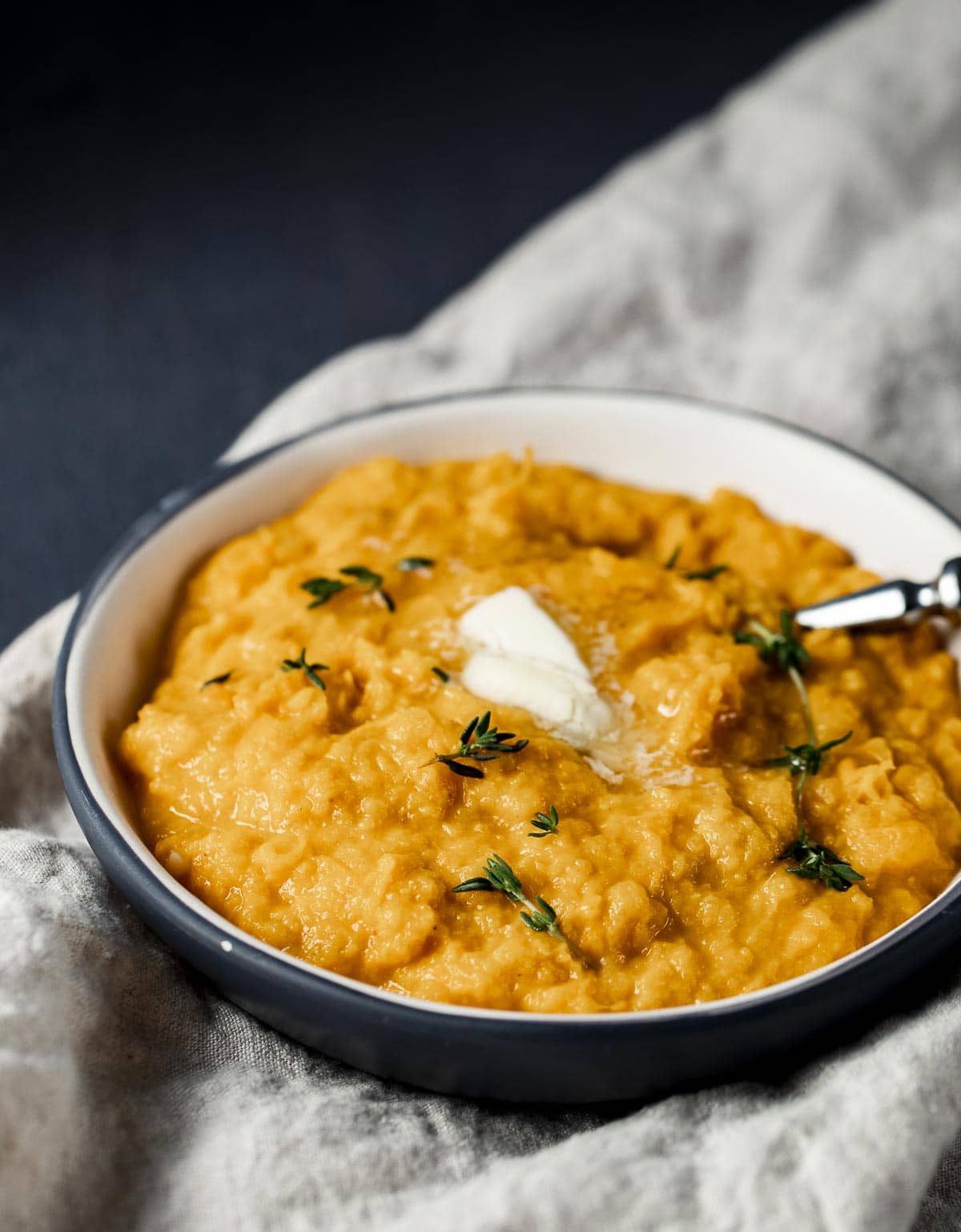 Side view of creamy sweet mashed potatoes in a bowl with a spoon inserted into it.