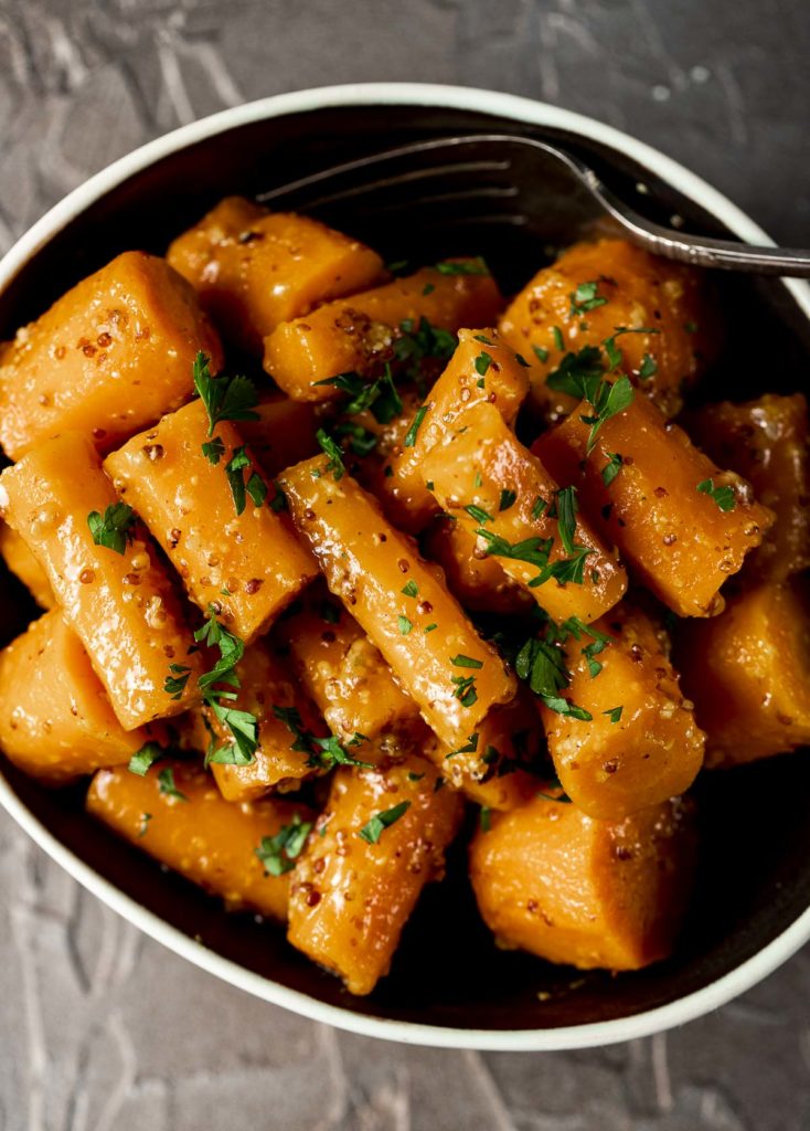Overhead view of honey dijon carrots in a bowl and topped with chopped herbs.