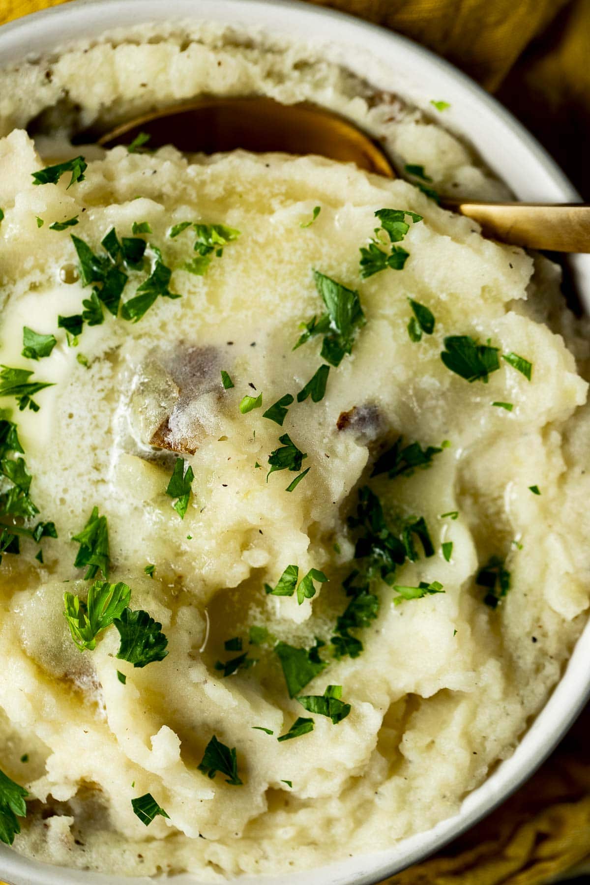 Overhead of mashed potatoes in a bowl and topped with fresh herbs.