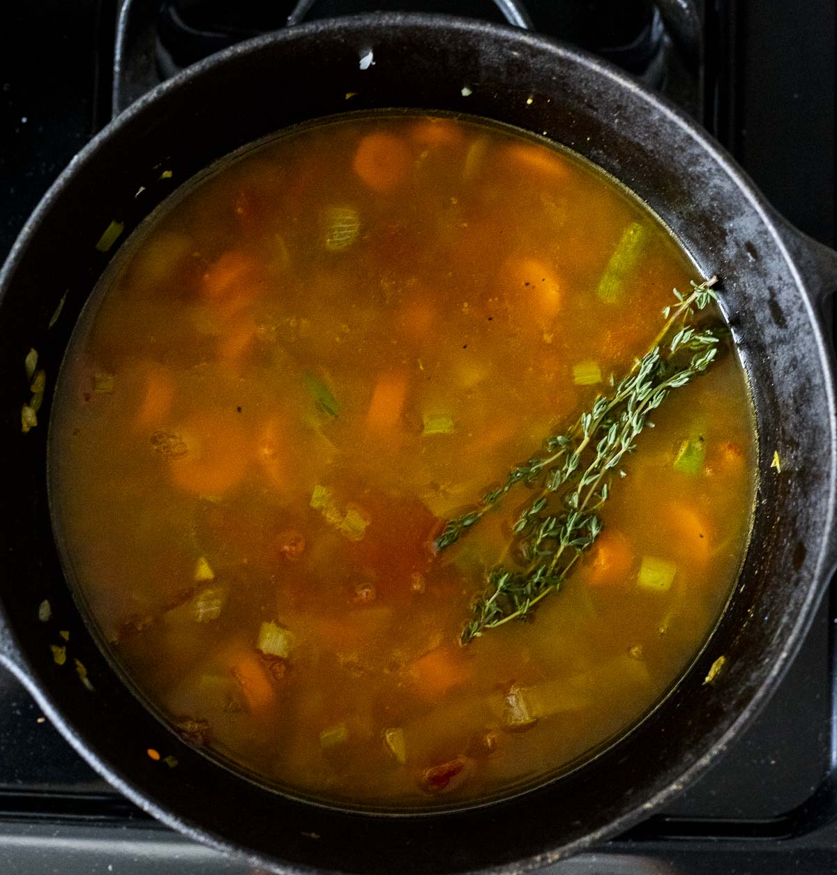 Turkey lentil soup in a large pot with sprigs of thyme on top.