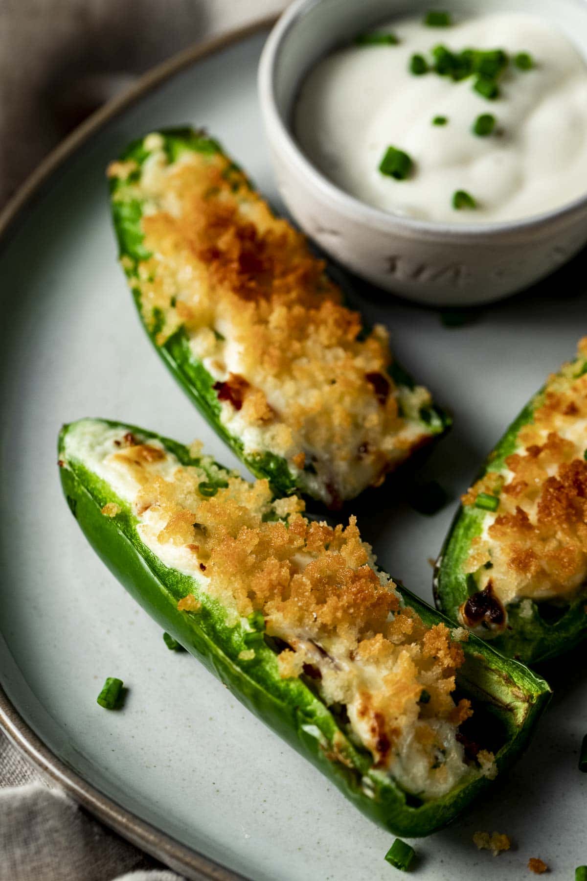 Jalapeno poppers arranged on a plate with dipping sauce.