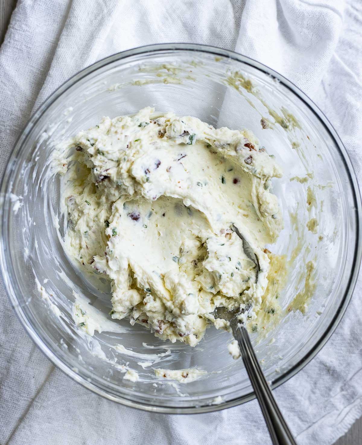 Cream cheese filling mixed together in a glass bowl with a spoon.