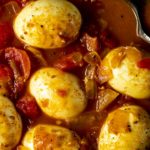 Close up of eggs in tomato and onion sauce.