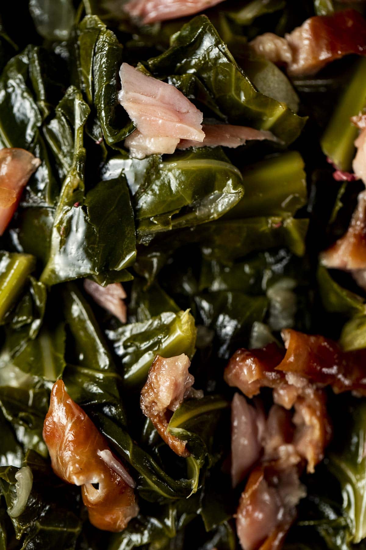Close up view of cooked collard greens with smoked turkey mixed throughout.