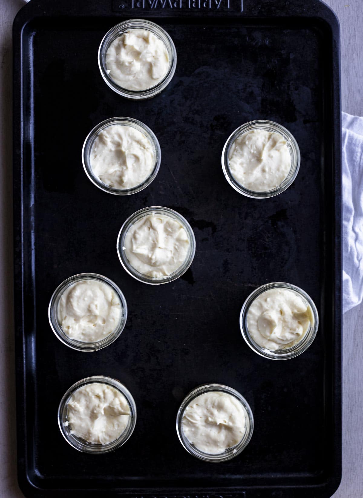 Cheesecake filling added to the jars and arranged on a baking sheet.