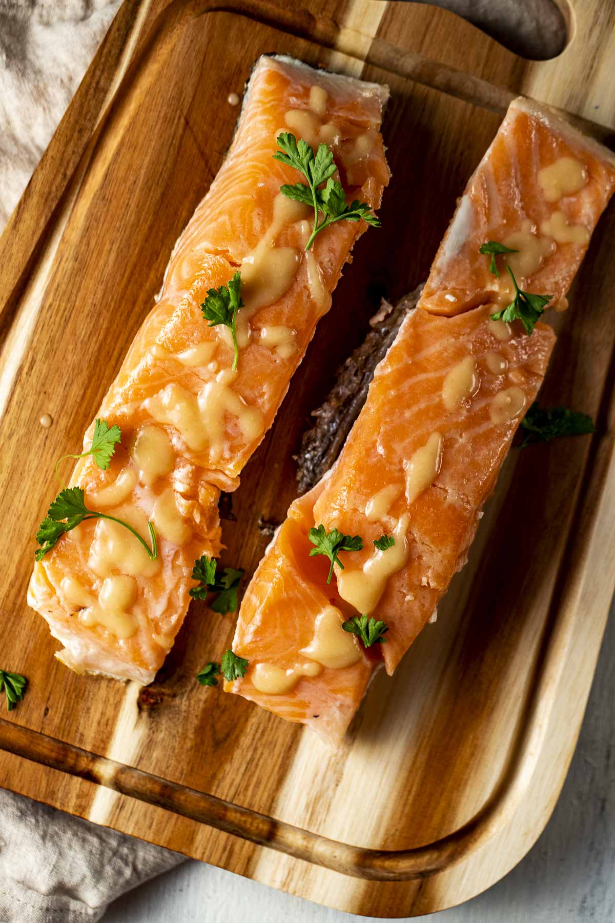 Overhead view of two salmon portions on a wooden board and topped with pineapple miso glaze.