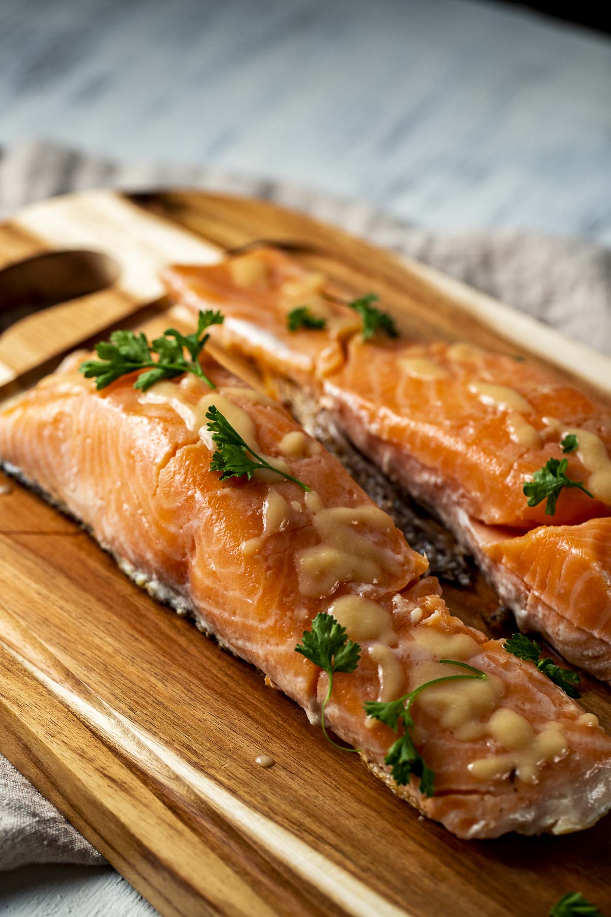 Two sous vide salmon portions on a wooden serving board.