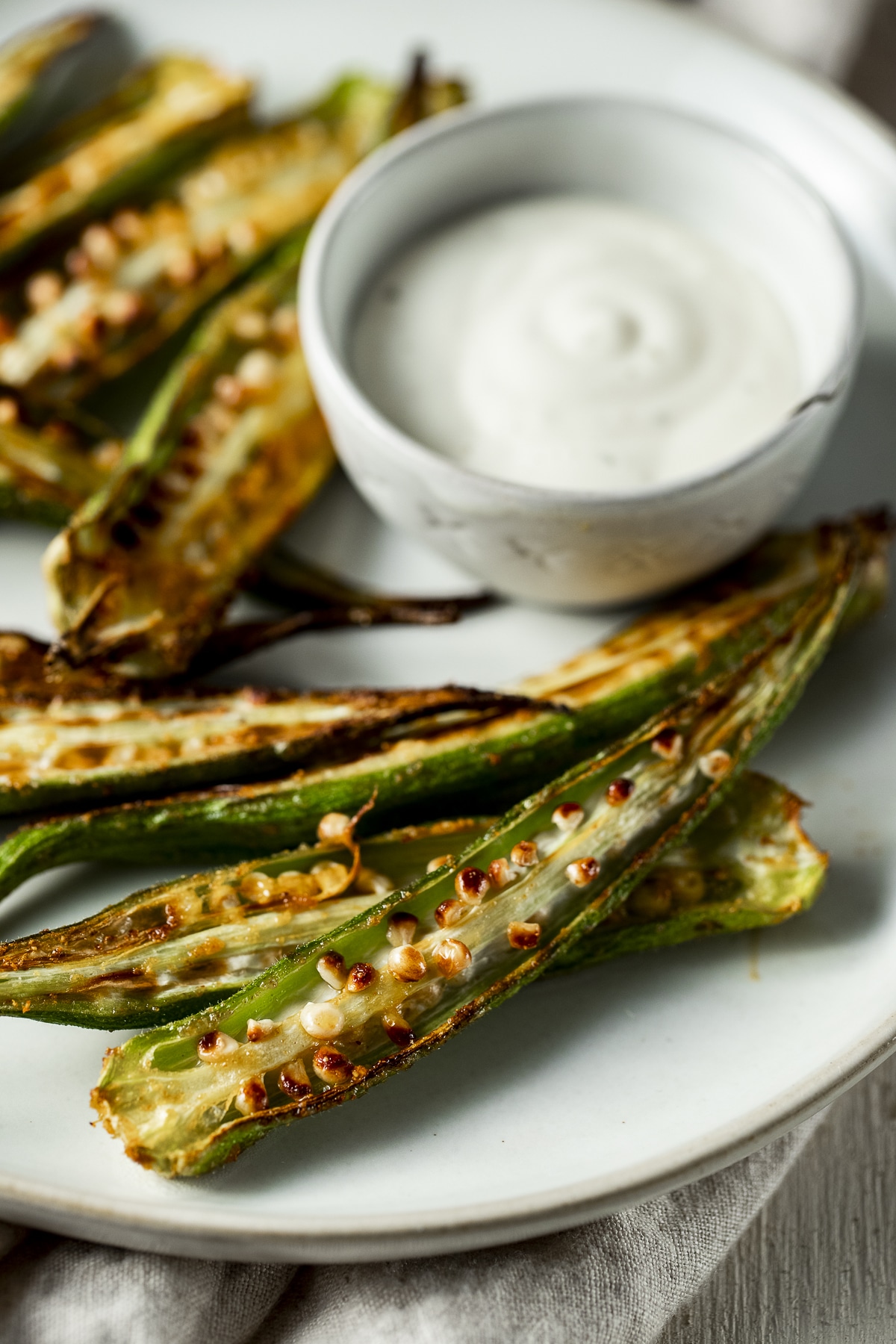 Okra fries on a plate with a small bowl of dipping sauce.