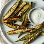 Overhead view of air fried okra on a white plate with dipping sauce.