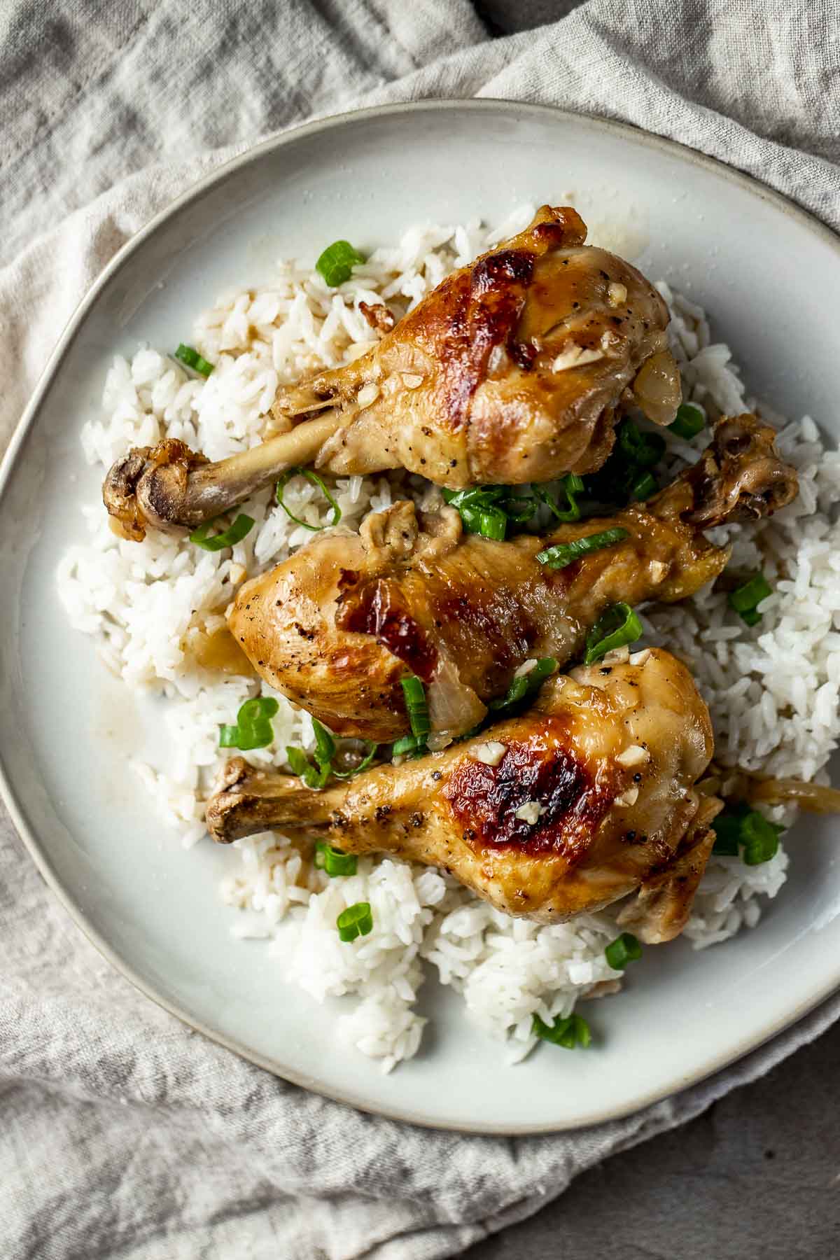 Instant Pot chicken adobo served on a bed of rice and garnished with chopped green onion.