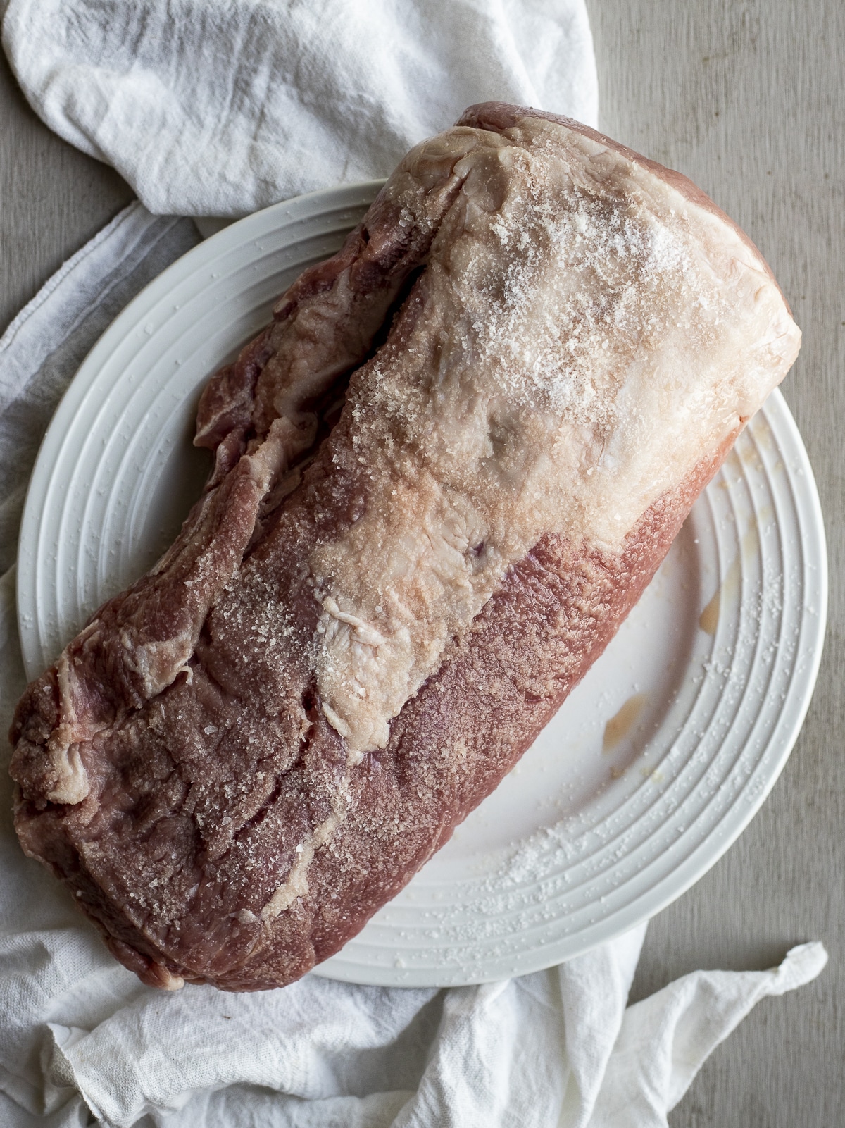 Salted pork loin roast on a white plate.