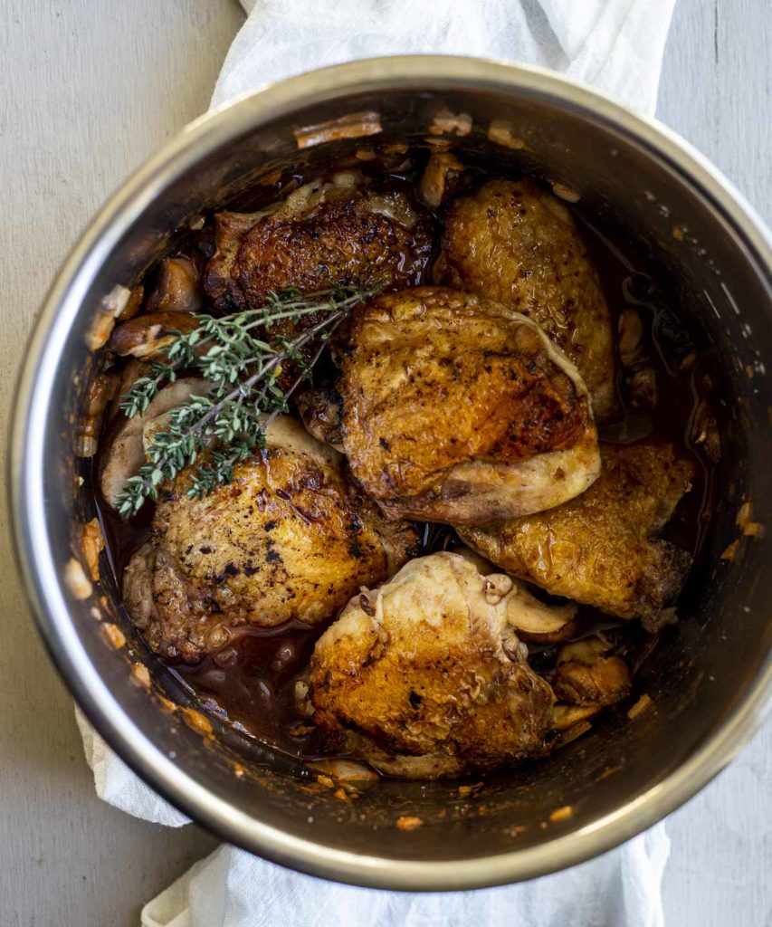 chicken in a pot with seasonings and vegetables