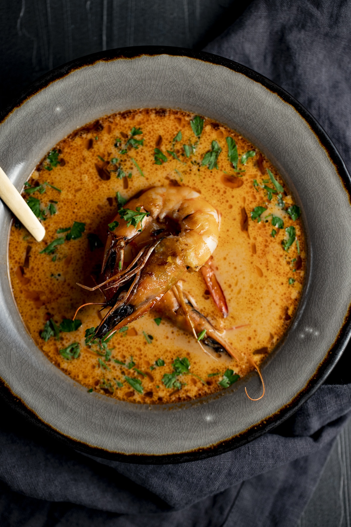 Overhead view of prawn bisque in a grey bowl and topped with prawns.