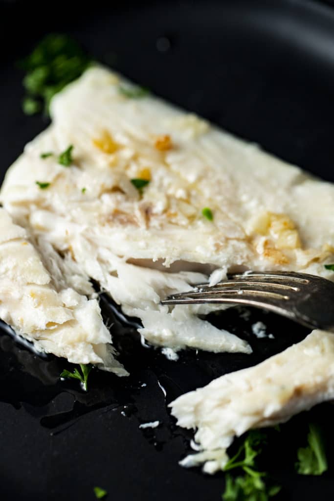 Halibut being flaked apart with a fork.