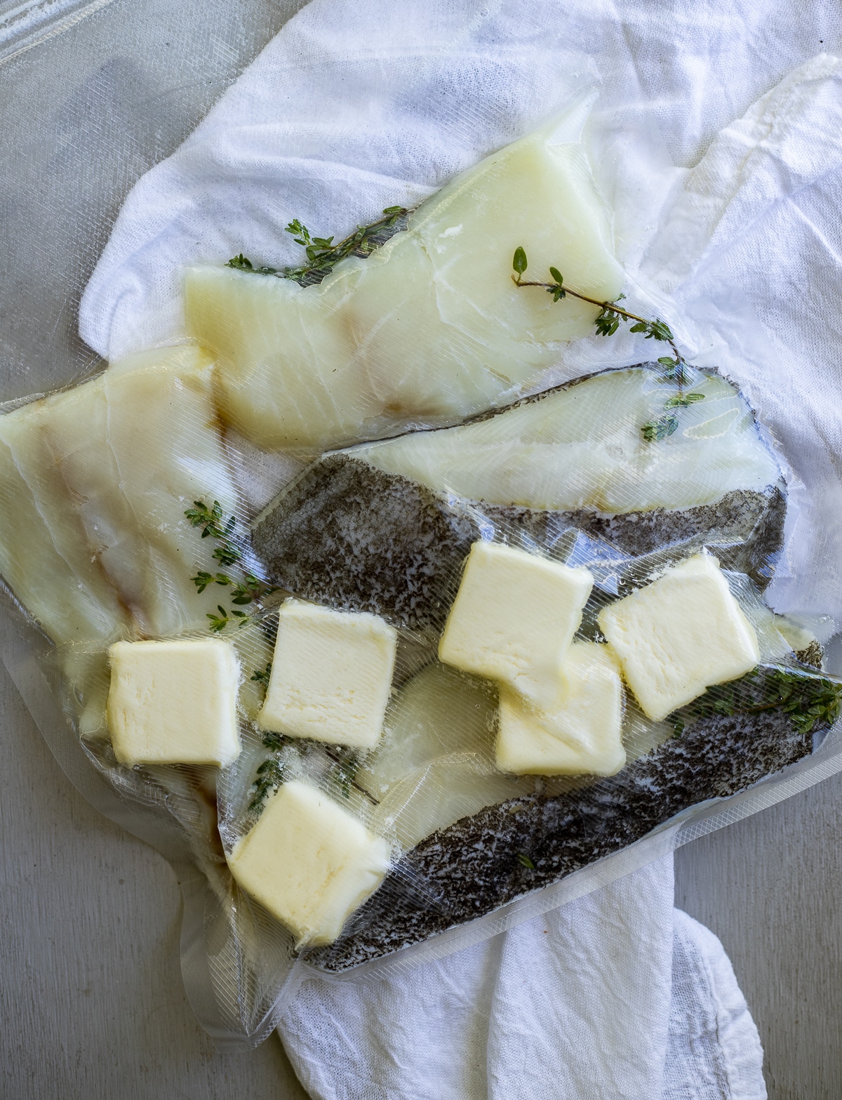 Halibut pieces sealed in a bag with butter and sprigs of thyme.