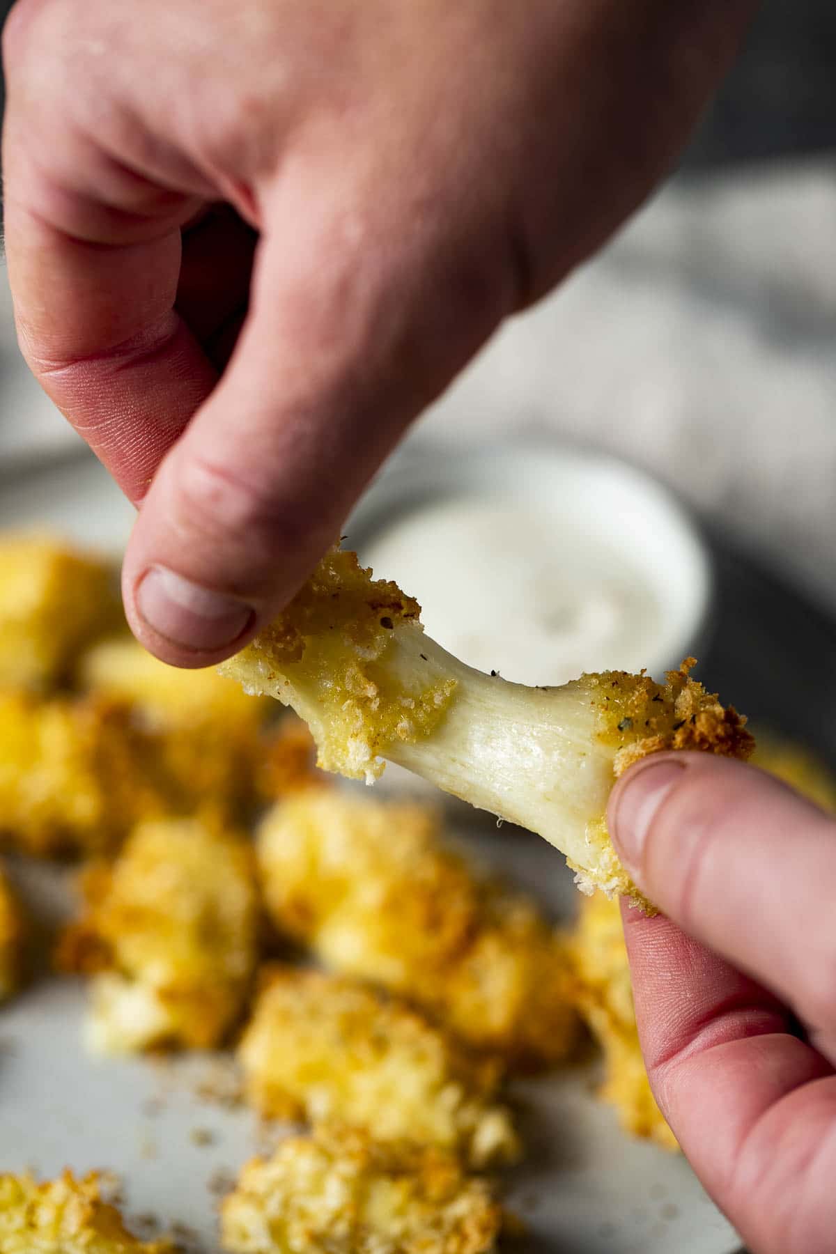 Close up view of an air fried cheese curd being pulled apart.