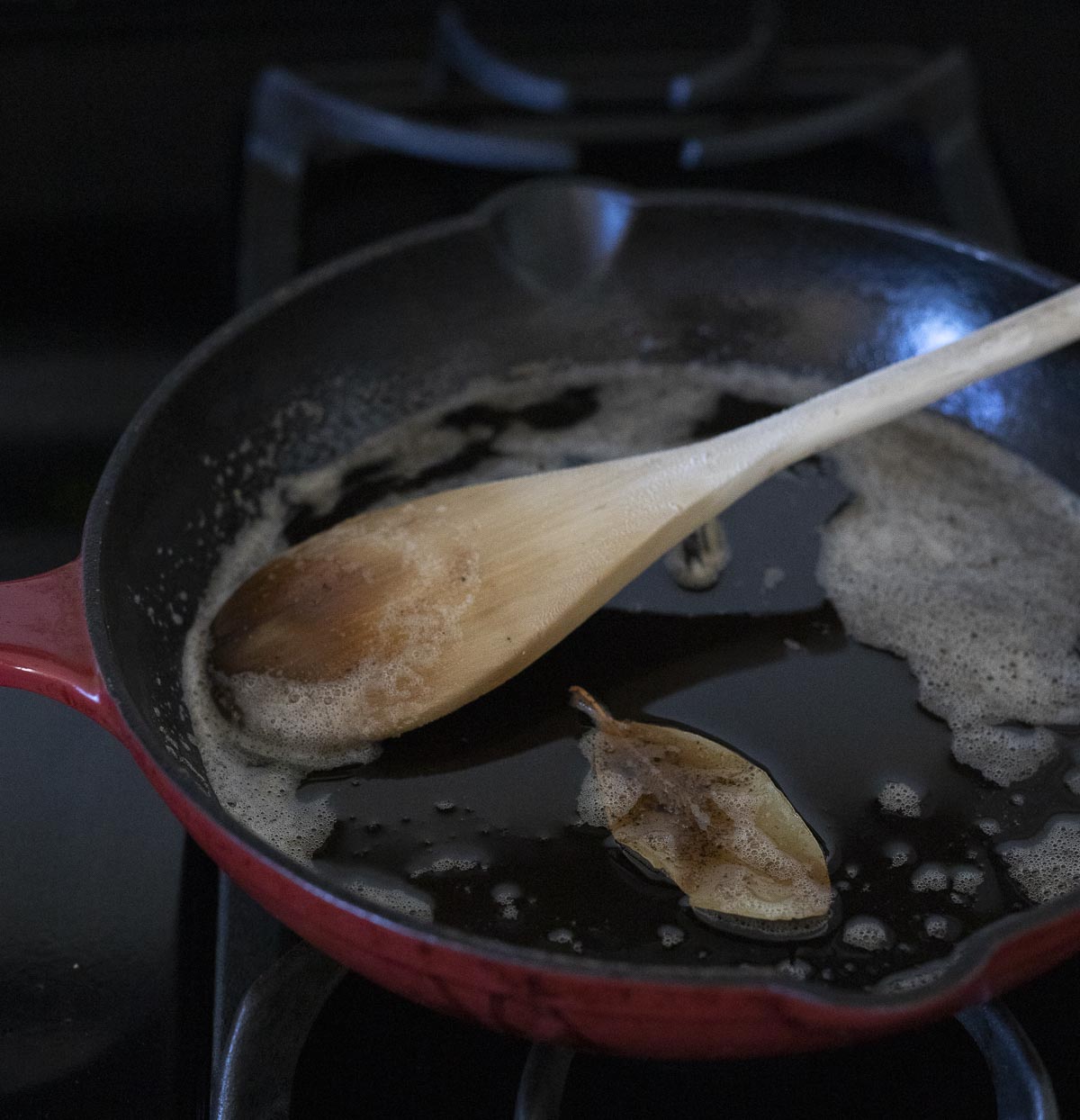 Browned butter mixture being stirred with a wooden spoon in a skillet.