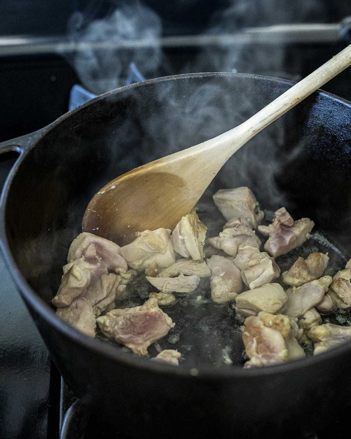 Chicken pieces being browned in a large pot.