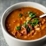 Instant Pot bean soup in a bowl with a spoon and topped with green onions.