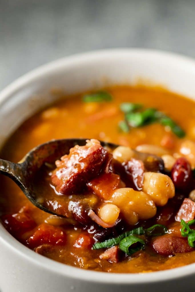 Close up view of a spoonful of bean soup being taken from a bowl.