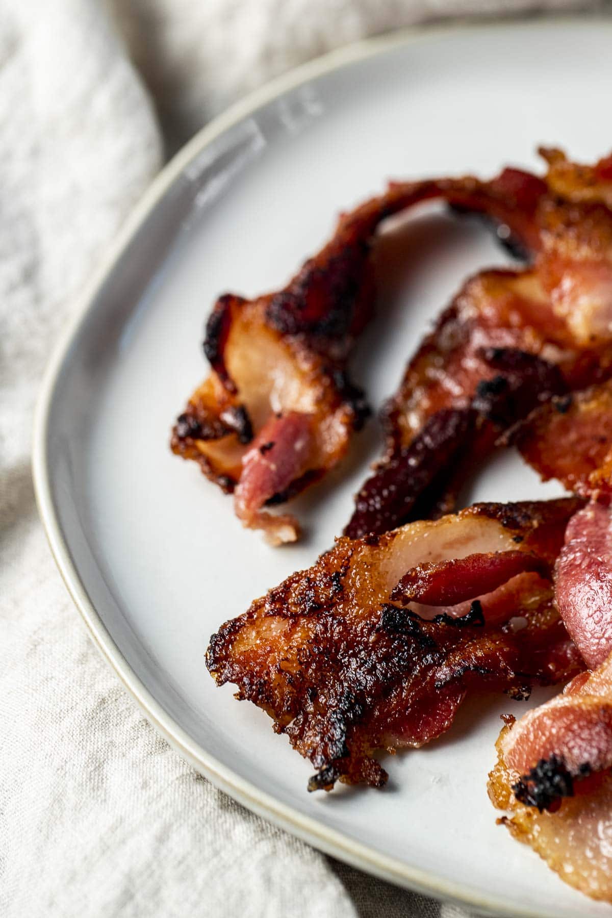 Side view of crispy bacon on a white plate.