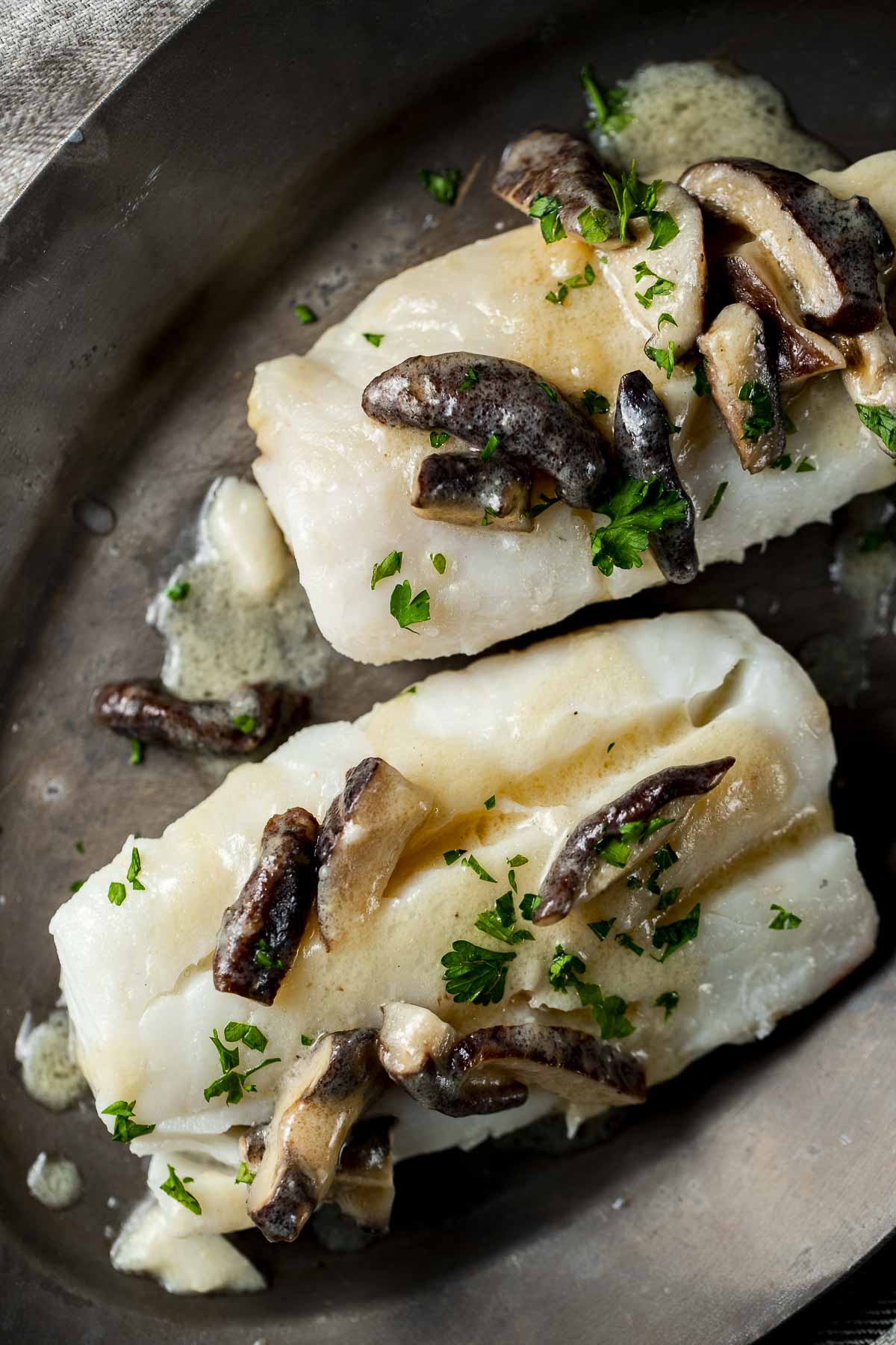 Two fillets of sous vide cod topped with mushroom sauce.