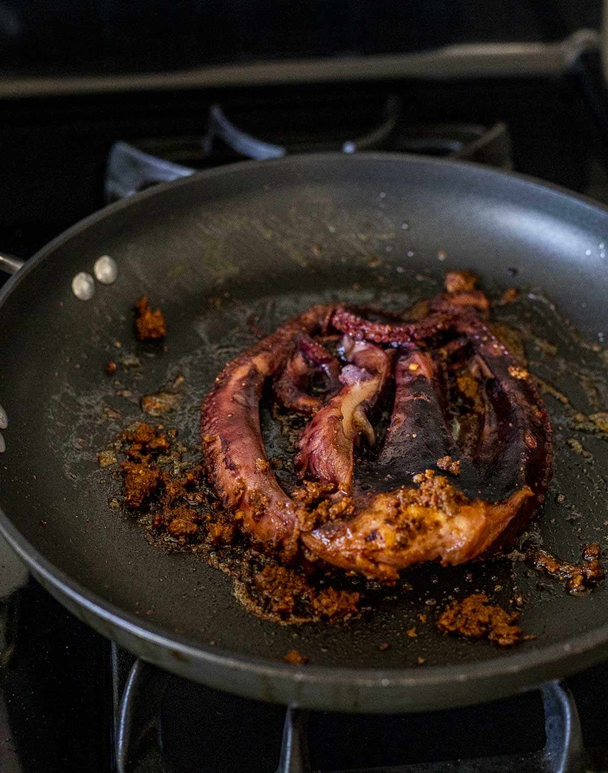 Sous vide octopus being browned in a skillet.