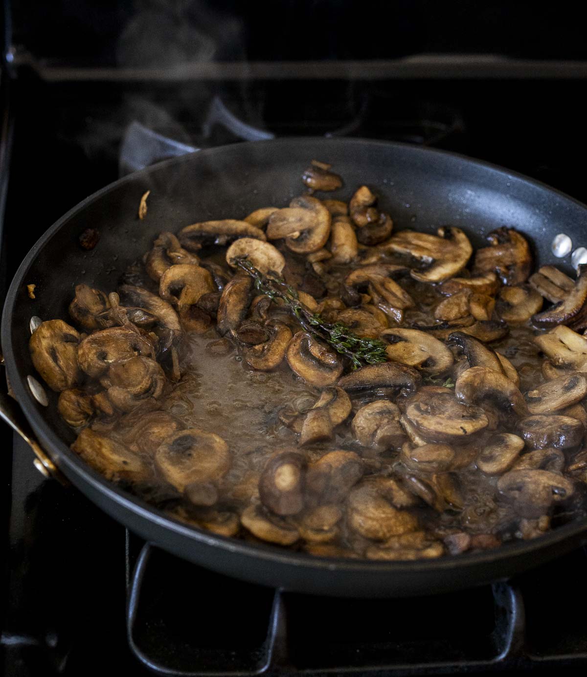 Sherry mushroom sauce cooking in a skillet on the stovetop.