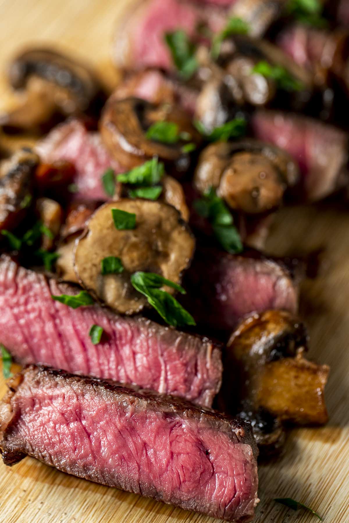 Sirloin steak slices topped with mushrooms and chopped herbs.