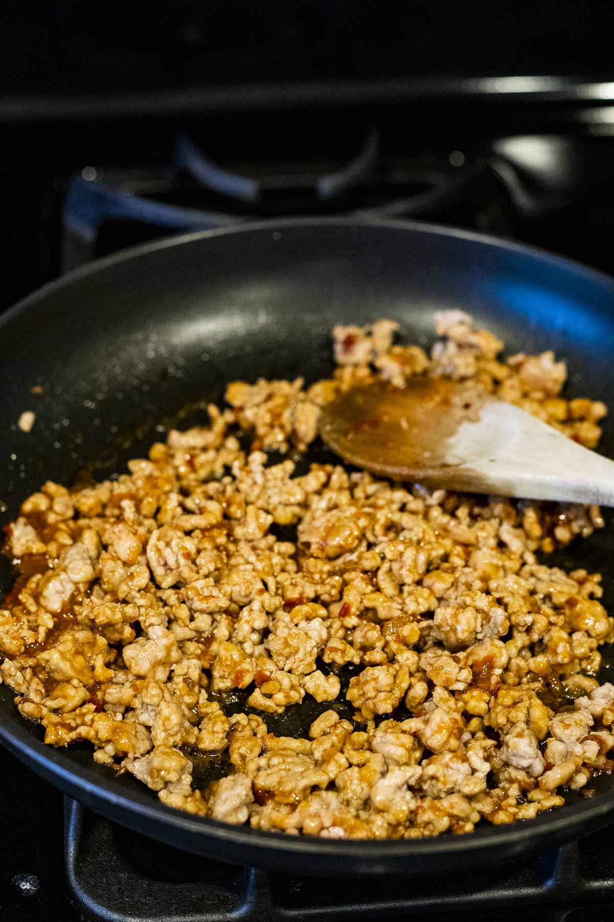 Ground pork cooking in a skillet on the stovetop.
