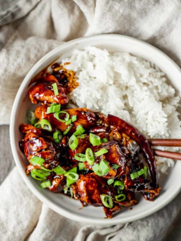 Overhead view of air fryer general tso's chicken served with steamed rice in a bowl with chopsticks.