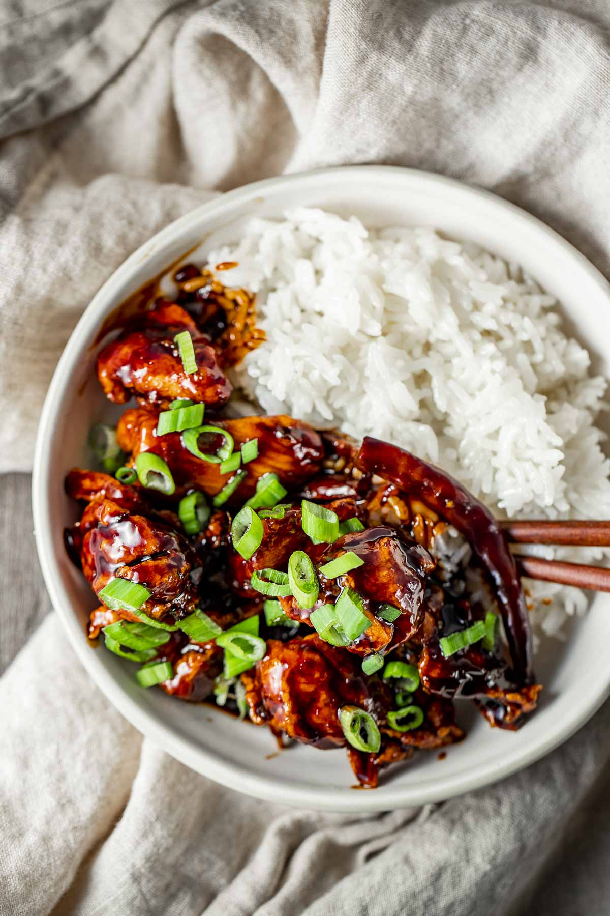 Overhead view of air fryer general tso's chicken served with steamed rice in a bowl with chopsticks.