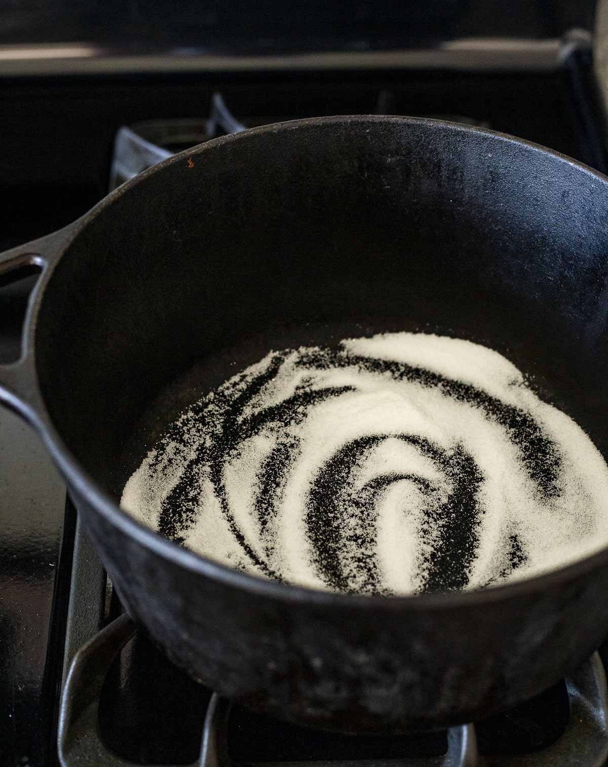 Granulated sugar in the bottom of a Dutch oven on the stovetop.