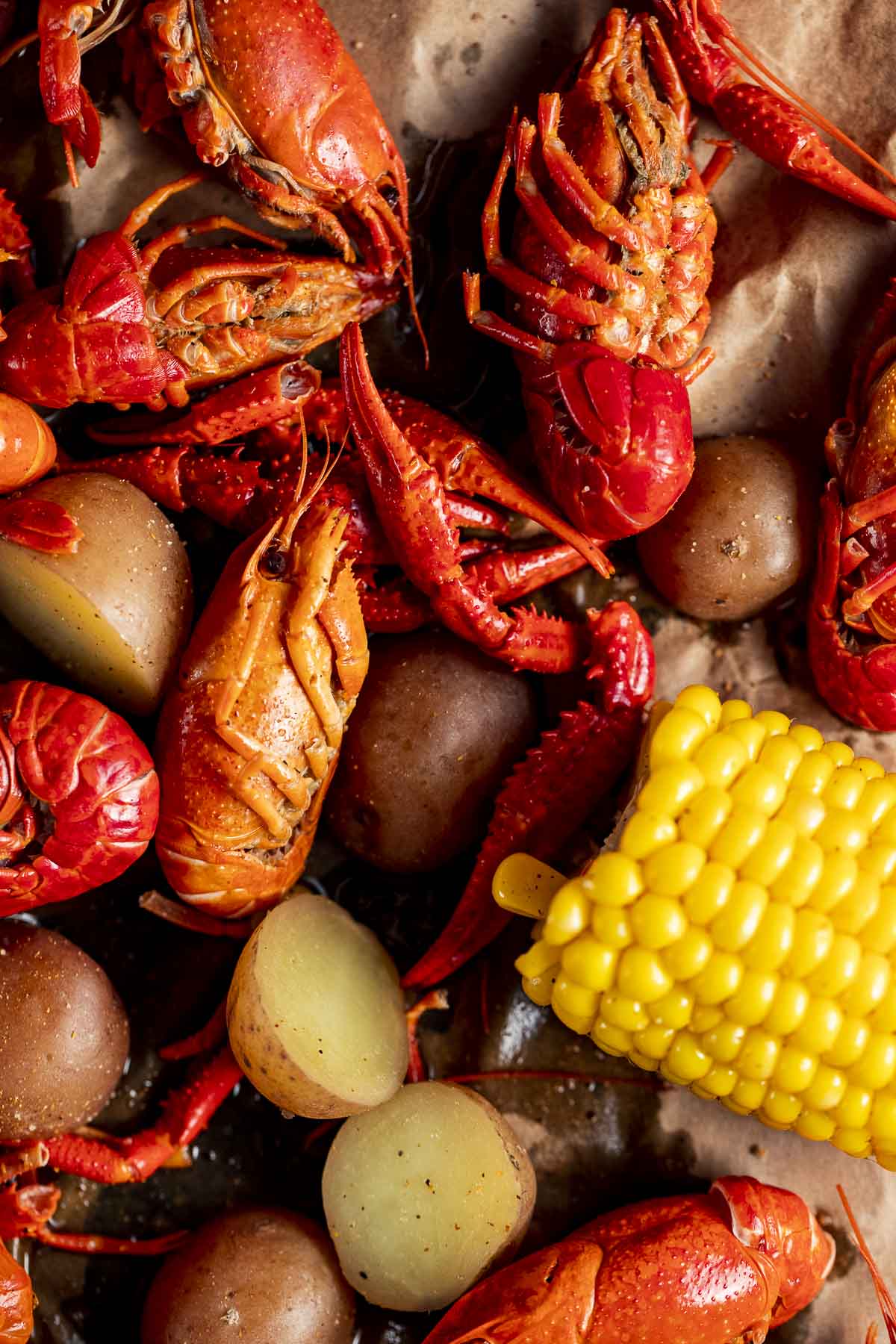 Close up view of boiled crawfish with corn and potatoes.