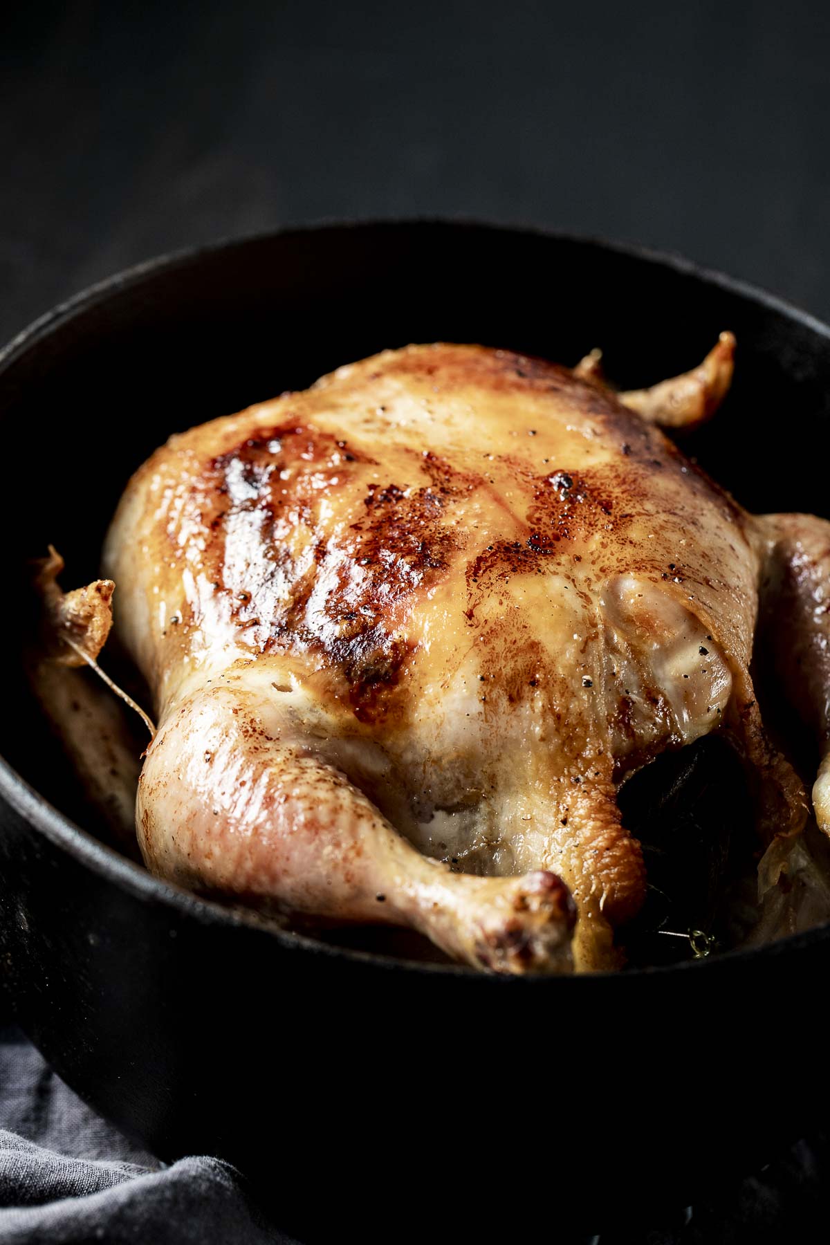 Side view of a whole roasted chicken in a Dutch oven.
