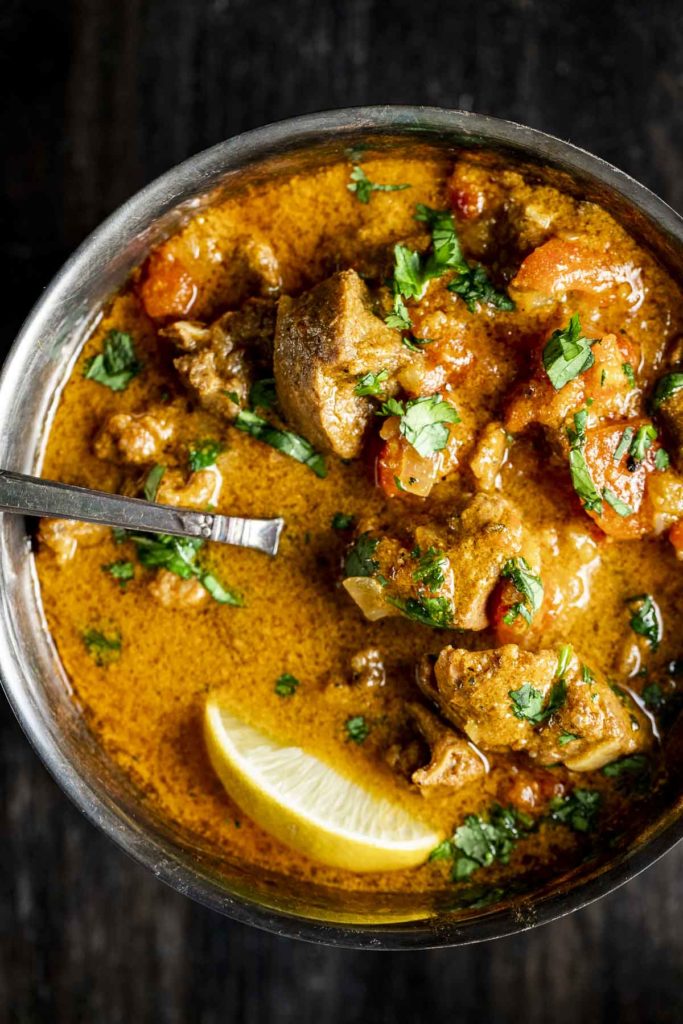Overhead view of lamb curry in a bowl with a spoon inserted into it.