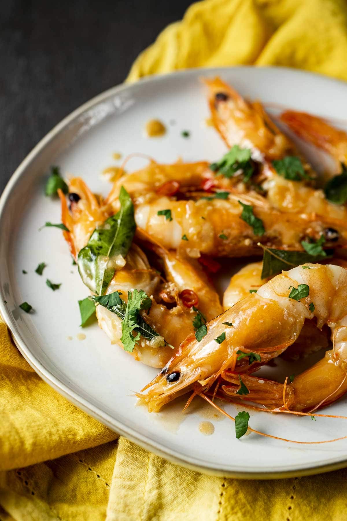 Butter prawns on a white plate topped with chopped cilantro.