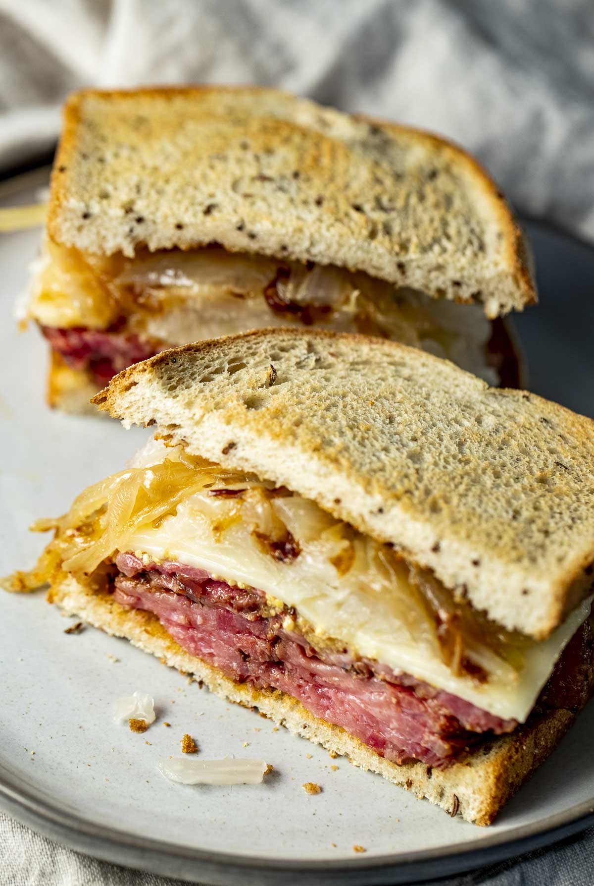 Pastrami sandwich cut in half and arranged on a plate.