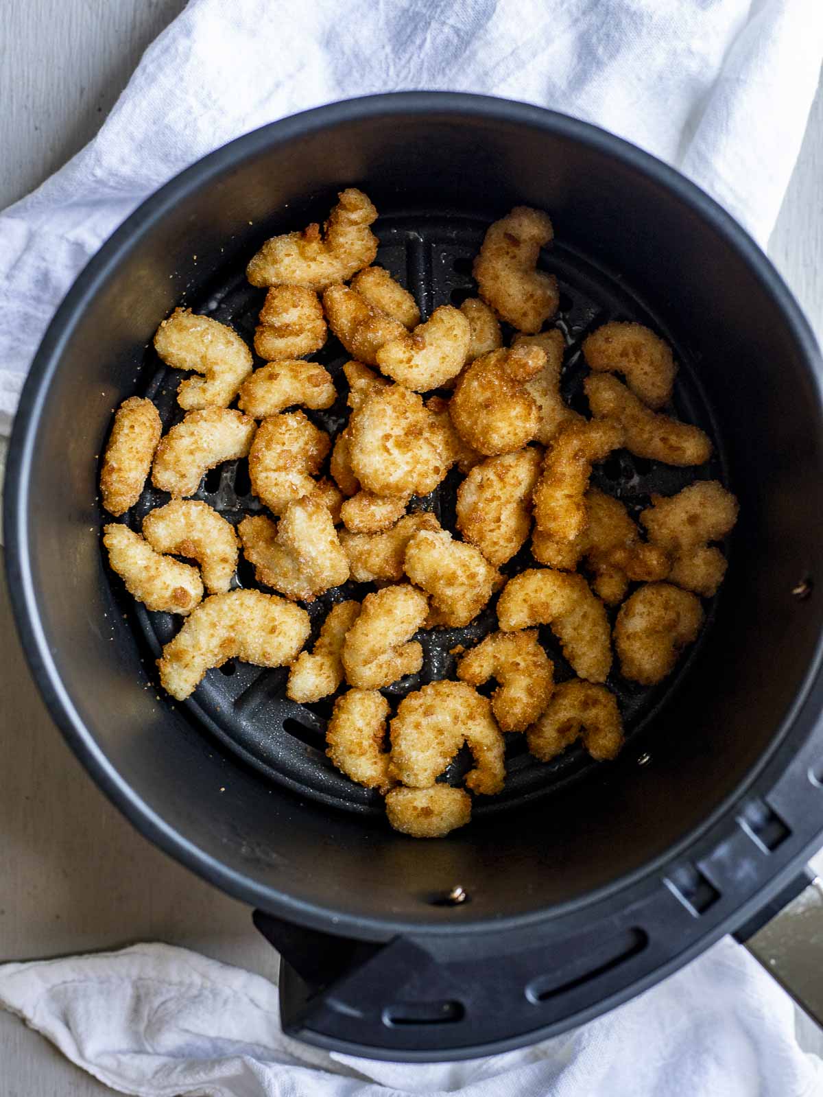 Popcorn shrimp in an air fryer basket.