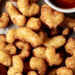 Close up view of golden brown and crispy popcorn shrimp.